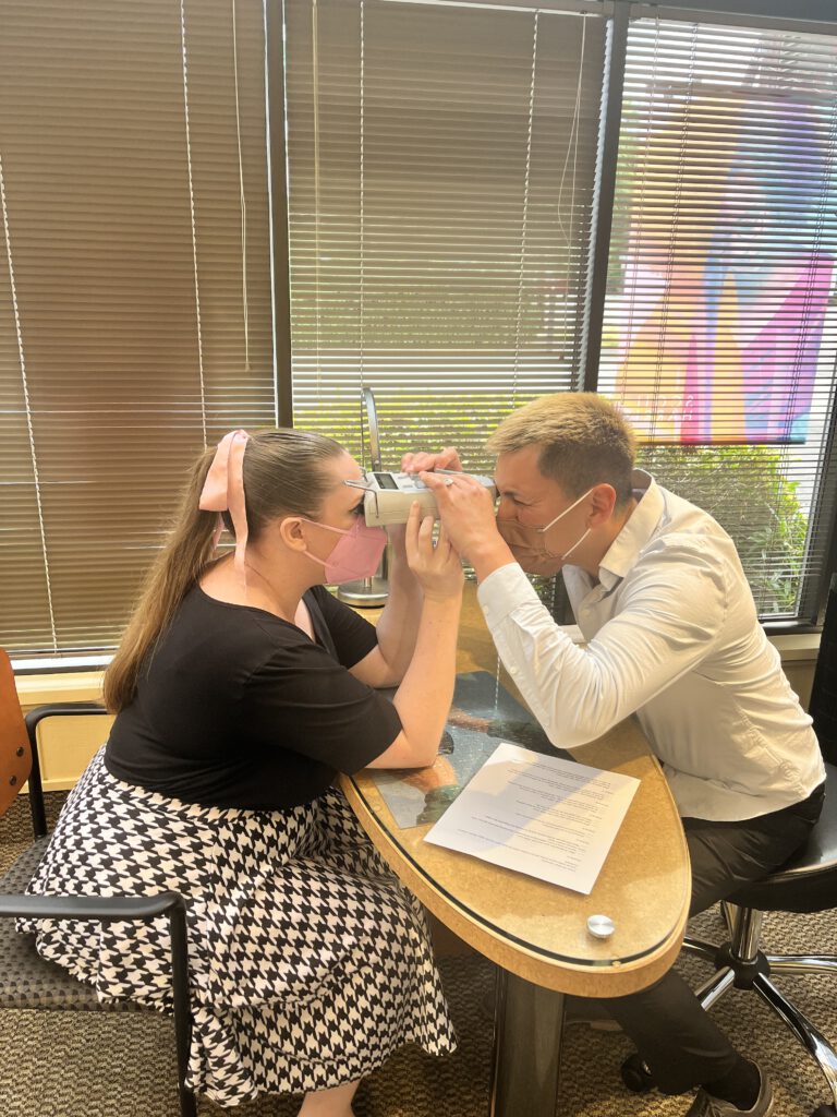 optician apprentice takes pupillary distance measurement
